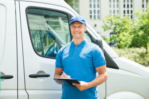 42544955 - young happy male worker in front of truck writing on clipboard
